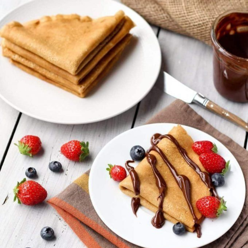 Homemade pancakes topped with berries and chocolate syrup